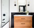 Delta Trinsic fixtures in Matte Black and School House Electric vanity sconces echo the black beadboard encircling guest bath, adding contrast against white porcelain tile floor and subway shower walls. Vanity countertop was installed by Venetian Stone Works.