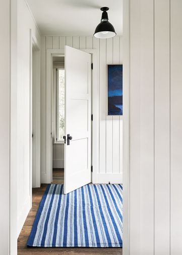 In this view from kitchen to powder room, one of Kathryn Riedinger’s paintings, “Moonlight,” adorns the entry - its watery hues echoed in the landscaped blue and white rug.