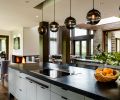 Kitchen updates include honing existing polished granite island countertop, refacing the cabinet doors, and tucking a series of task-lighting pendants by John Pomp into a recessed ceiling. Mayer Design, Inc. custom standout metal and cast glass nook table is a focal point. Sun Valley Bronze hardware on the cabinets completes the look.