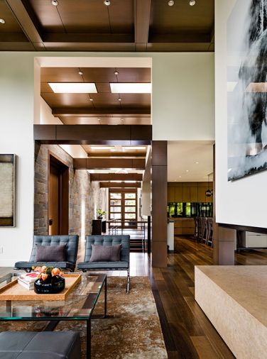 A pair of Design Within Reach Barcelona chairs flank the cast glass top Mayer Design coffee table to reveal the Driscoll Robbins showpiece rug beneath. Three-sided fireplace features Teriesta limestone slab from Meta Marble & Tile. Hall console table by Nicholas Mayer.