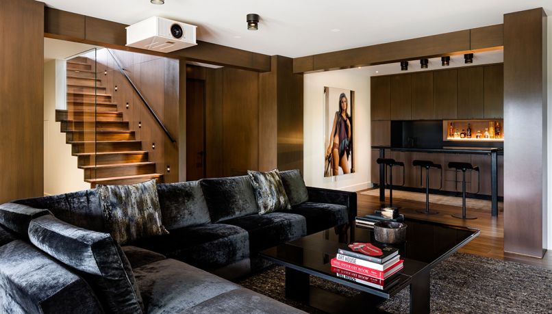 Existing central staircase was given a facelift by opening the wall up with glass, newly paneled wall and stair light. A Terry O’Neill print of Rachel Welch spices up the scene. Bar stools by Inform Interiors. Mayer Design coffee table.