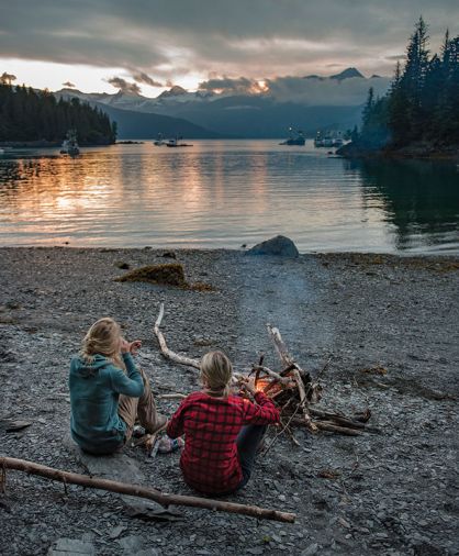 After a long, hard summer’s day of fishing in Alaska, Laukitis and Neaton relax on shore before a fire made of driftwood, where they feast upon the beauty of their world.