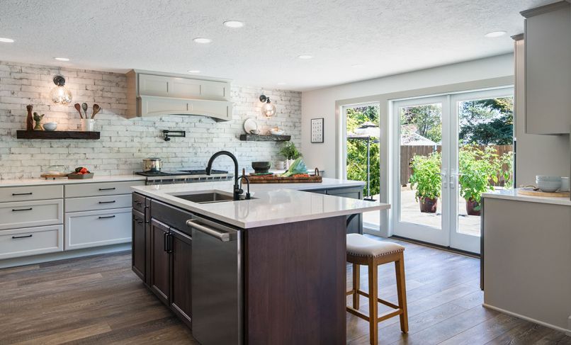 The focal centerpiece of the kitchen is an L-shaped island that serves multiple roles. Floor-to-ceiling DeWils cabinets and drawers provide the storage space that in a more traditional design would be supplied by upper cabinets. The counter-height casual eating area is the segue between the kitchen and formal dining room. Windows above the buffet open to access an exterior bar made from weather-resistant Dekton by Cosentino.