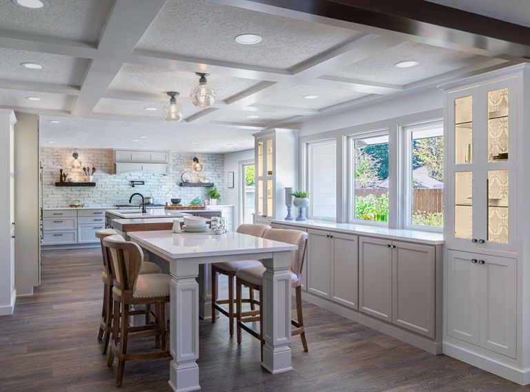 A rustic ceramic subway tile reaches from the countertop to the ceiling and echoes the tones used in both the revamped kitchen and casual eating area. Counters throughout are Cambria Torquay quartz. One window grew to a larger window and French doors to allow access to the large backyard and to let the light stream in. The couple, who are not fans of upper cabinets, limited their use to one corner, which provides a coffee station.