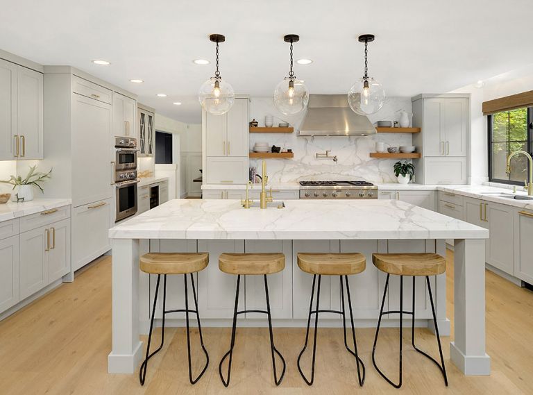 The mixed use of metals in the Thermador stovetop and hood, and brass pot-filler faucet and cabinet hardware work to add some sparkle to the room’s other surfaces. Open shelving provides convenient storage for plates, bowls and other dishes.