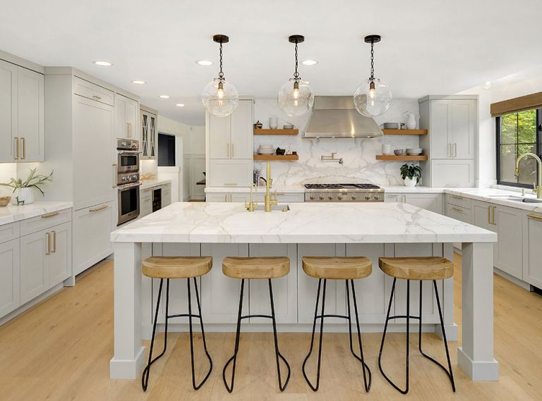 The mixed use of metals in the Thermador stovetop and hood, and brass pot-filler faucet and cabinet hardware work to add some sparkle to the room’s other surfaces. Open shelving provides convenient storage for plates, bowls and other dishes.