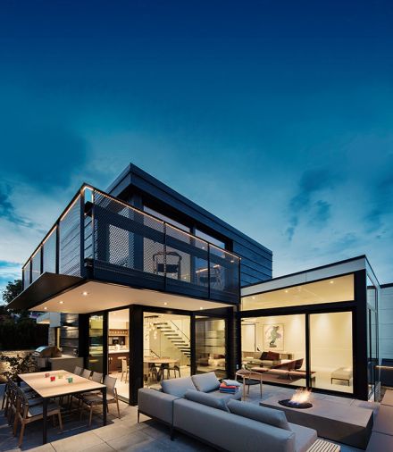 Outdoor living spaces beneath Shou Sugi Ban tower and cantilevered study balcony. Cantilevered staircase floats amidst living area. Master bedroom beyond.