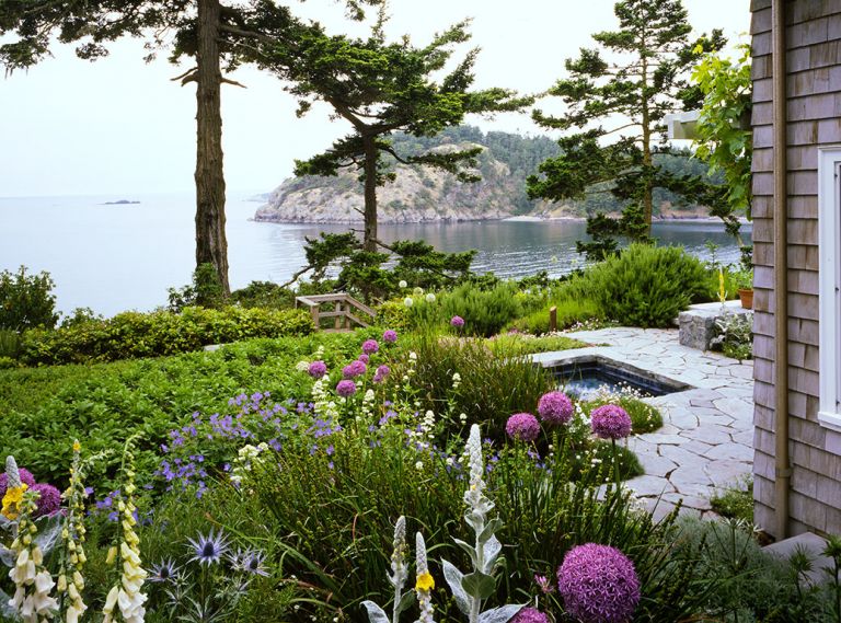 The bay is visible from the pathway of locally quarried alger granite steppingstones that lead past the sunken spa to the original reconstituted staircase to the beach. Lynne suggested salvaging the women’s pebble mosaics which Broadhurst fashioned into a pathway down the cliff face. Big Blue Sea Holly (Eryngium zabelii), foxglove, mullein, libertia, Johnson’s Blue geraniums and allium flourish alongside one another. The main terrace is at right. Broadhurst’s newly designed Sun Garden left.