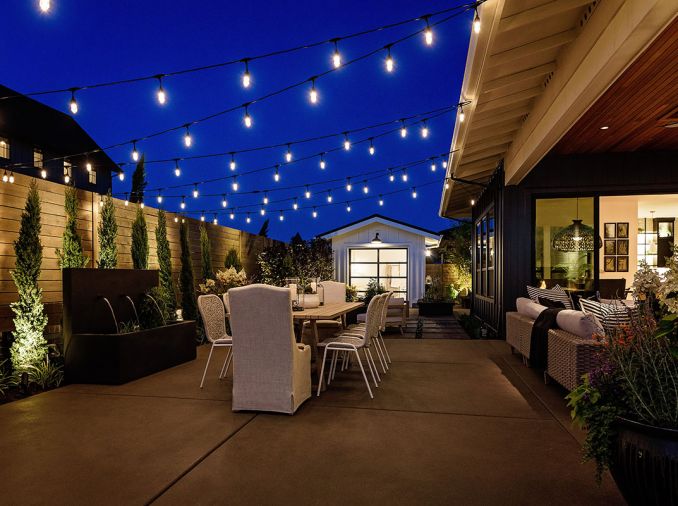 Covered outdoor dining area right faces garden area framed by triple-faucet fountain and horizontal cedar fencing for privacy. Outdoor furniture form KEY Home Furnishings.