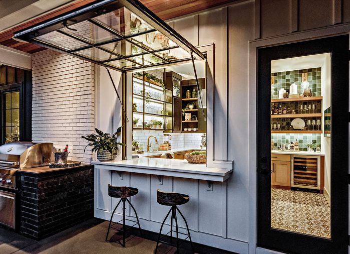 James Hardie board and batten siding frames hydraulic-raised pass-through window by Wisconsin Parrett. Heated covered living area above BBQ with non-combustible painted brick reiterating home’s façade.