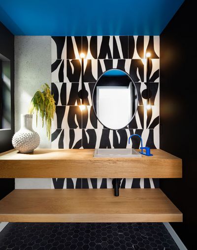 Adjoining the kitchen, the powder room generates talk with its blue ceiling, blue faucet and zebra-like black-and-white wall tile.