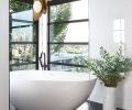 A long shower room in the master bath is anchored at one end by a white, freestanding soaker tub from which bathers can enjoy views of Lake Union. Black penny marble tiles cover the floor and the brass light fixture is approved for a damp location.