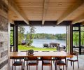 The new home, built to fit the vernacular of the historic compound, is situated on a knoll above great lawn looking toward Salish Sea through Quantum aluminum clad lift and slide doors. Custom dining table with stackable DWR profile chairs.