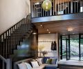 Mudroom entry features chandelier with 12 vintage glass floats lighting the painted staircase. Rustic plywood ceiling upstairs contrasts with refined lower. Custom banquette has steel magnetic message board above. Black Tusk Basalt flooring inside and out.