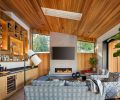 The fireplace brings warmth to living area beneath water-based stained cedar ceiling. Custom white oak liquor cabinet by Warm Tones Woodworking. Interior design by Joelle Jarvis. Wine cooler Eastbank Contractor Appliances.