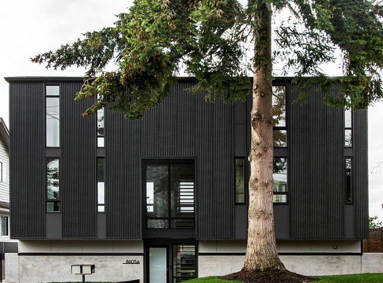 The home’s corrugated metal exterior creates its architectural splendor. Window above entry features perforated metal screen reiterating interior staircase design. Entry walkway adds unexpected diagonal angle to save existing tree’s roots. Evergreen tree provides year-round privacy.