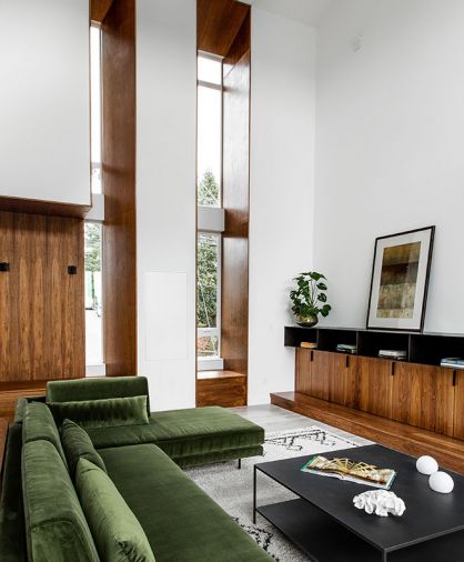 LDB Homes furred out wall to install a pair of deep-set Ply Gem windows trimmed in handsome walnut that rise over 20' to meet the stunning angled ceiling. Cozy reading nook at left is tucked within wall thickness.