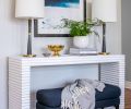 Mr. Brown concrete console table adds graphic appeal to staircase wall. Lawton creates “flex” furniture opportunities with another West Elm bench easy to pull into living area. Pair of console lamps echo brass accents found elsewhere.