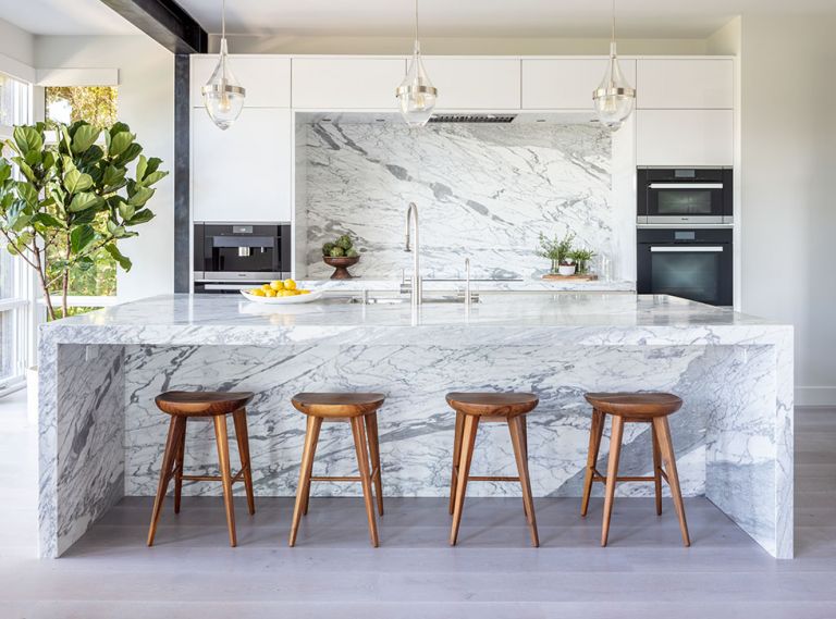 Blackened steel structural moment frame for seismic resilience draws eye to sleek, handleless SieMatic upper cabinetry. SieMatic’s streamlined profile perfectly frames the dramatic Calacatta Statuario honed marble backsplash from Meta Marble and Granite. Moon raises the Thermador exhaust hood to showcase it. Same marble island features waterfall bookends. Waterstone faucet paired with Julien sink. Trio of Tech Lighting pendants. A pair of Electrolux refrigerators/freezers are joined for larger storage opportunities. Lengo Bastone wide plank ROMA European Elegance, European White Oak flooring.