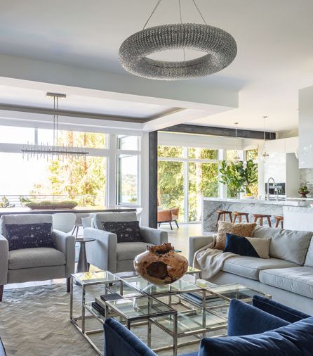 RH Crystal Halo chandelier brightens RH Keane stainless steel and glass square coffee table below. Moon reveals blackened steel moment structural frame separating kitchen from formal dining area. Box beamed dining room ceiling element continues the visual delineation.