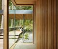 A glass corner in the hallway has a view of the exterior path to the entry, and shows how interior and exterior materials echo one another for easy flow between inside and out.