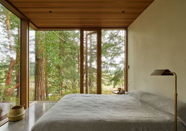 In the bedroom, glass walls frame picturesque views of the preserved trees.