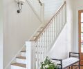 A graceful stairway clad in tongue and groove paneling with traditional railings leads to the upstairs guest retreat.