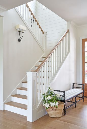 A graceful stairway clad in tongue and groove paneling with traditional railings leads to the upstairs guest retreat.