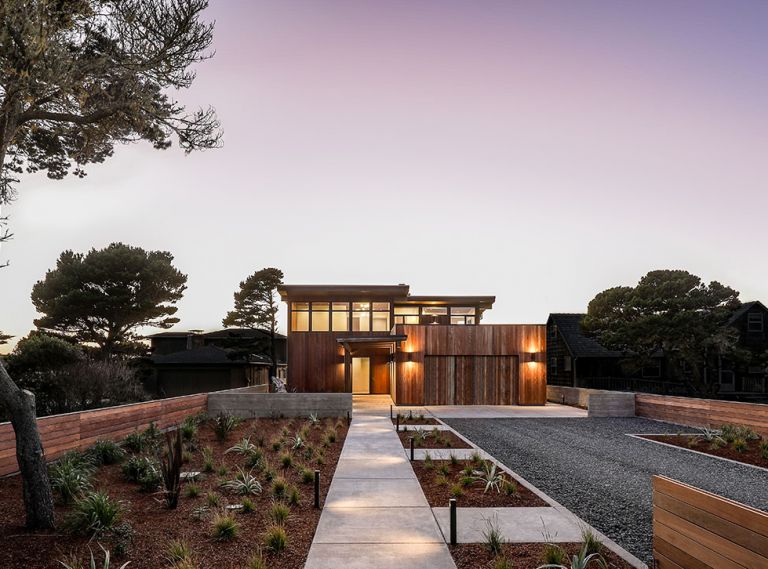 GSW Architects angled beach house to adhere to Bandon, Oregon, ordinance that determines tight setback along ocean so as not to obscure neighboring houses’ site lines. Garage at right with year-round succulent roof garden. Covered walkway to entry. Ipe tongue and groove siding with Lifetime Wood Treatment. Kolbe windows above. Marvin front door. Sense of traveling through landscape enhanced by low entry walls, easy-to-maintain coastal landscape, informal gravel driveway.