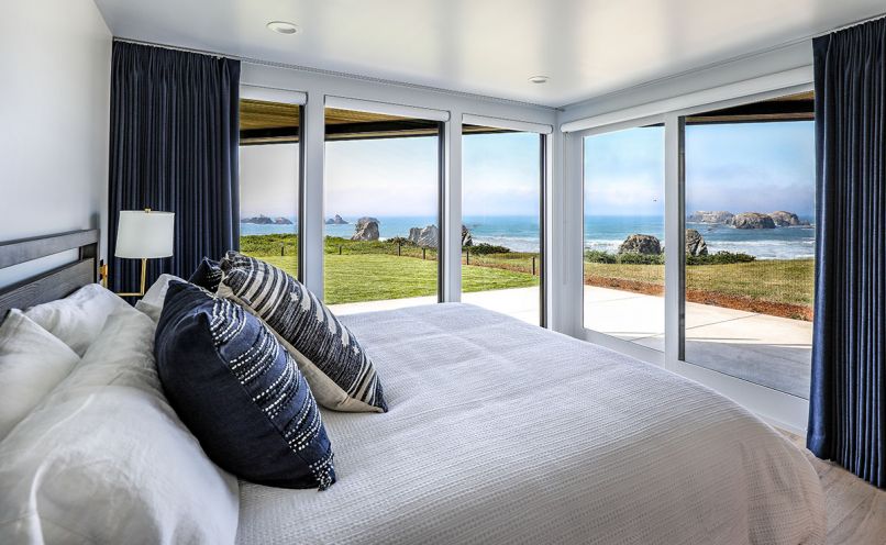 Each bedroom has its own personality; this guest bedroom features nautical navy draperies framing Princess Ewauna’s kittens left and Face Rock right.