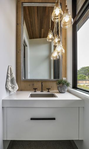 Powder bath features three individual Uttermost light fixtures. Black Alno hardware pops against cabinetry.