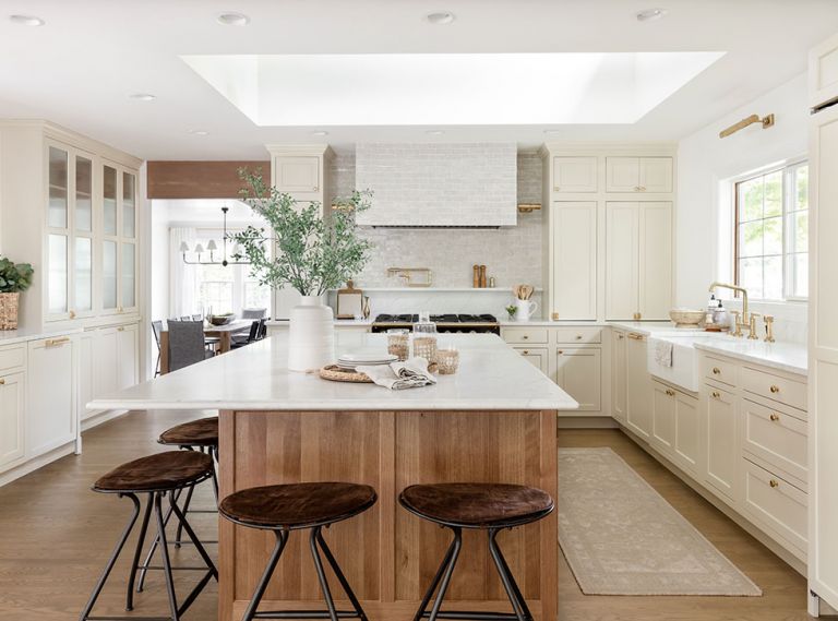 Interior designer Geneva Ness remodeled her Woodway, Washington home to be both elegant, and a cozy refuge for her family. The new kitchen has creamy Shaker-style cabinetry and brass accents, including pulls from House of Antique Hardware, an unlacquered brass kitchen faucet by Kallista, and picture lights found at Visual Comfort. Reggie counter stools from McGee & Co. offer striking contrast – and a place for the family to gather.