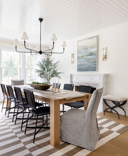 “I didn’t want it to feel like a museum, where you walked in and couldn’t touch anything,” says Geneva of her home. The furniture selection is classic and comfortable. THIS PAGE In the dining room, leather chairs and upholstered head chairs, both from Crate & Barrel, surround a table from Restoration Hardware. Artful lighting, including wall sconces and a Thomas O’Brien chandelier, both by Visual Comfort, produce an inviting glow. The Lulu and Georgia rug warms the red oak floors.