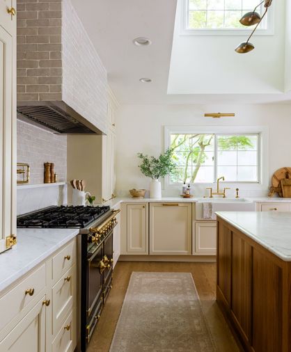 Zellige tile from Cle wraps the stove hood and backsplash behind the LaCornue range, while McGee & Co’s Persian-style runner leads to a Fireclay farmhouse-style sink tucked under the windows.