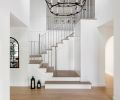 In the entry, a brass and stainless-steel stair railing and oversized chandelier by Visual Comfort are elegant additions.