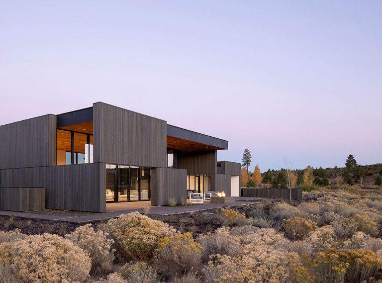 Corey Martin’s experience as a sculptor focused on making form inspired by the landscape contributed to his vision of creating architecture more intrinsically connected to Central Oregon’s unique geological landscape. Rooted in the surroundings of sagebrush below and endless skies above, Hacker Architects carved out this home as one whole from inside out. Dramatically stained Western Red Cedar on the exterior is naturally finished on interiors that extend from courtyard to kitchen. At far right is a small courtyard off the great room. An in-ground spa off the primary bedroom is sheltered by a louvered trellis above.