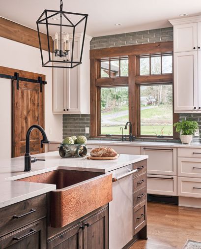 Thompson Traders hammered copper apron sink provides warmth against striking Ann Sacks profile beveled brick backsplash in Platinum Irid. Calcatta Natura Corian quartz countertop with Hansgrohe rubbed bronze faucet.