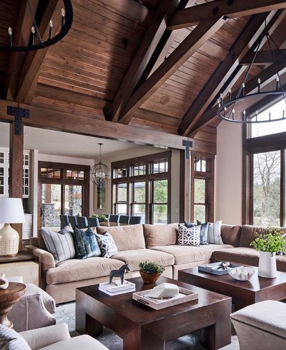 A Parsons square cocktail table in Caramel echoes towering overhead beams. Sea Green accent pillows continue water theme found in Bernhardt Mosaic Side Chai dining chairs. Currey & Co. Broxton Orb bronze dining room chandelier gleams before Sierra Pacific windows.