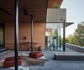 Gym is visible through entry courtyard cooled by Big Ass “Haiku” fan. Pair of red leather poufs by The Citizenry cozy up to Paloform Robata 72 concrete fireplace.