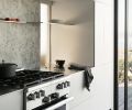 Custom durable Corian kitchen cabinetry in Glacier White found on top floor. Satin-etched glass pass through door to scullery. Bianco Treviso marble backsplash. Miele range and hood.