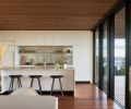 Mater MD Counter Stools in Sirka Gray stained Beech tuck beneath island overhang. Waterfall island countertop echoes range marble backsplash.