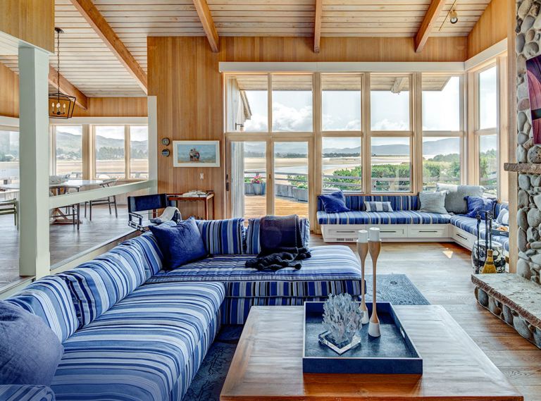 Bold, beachy stripes anchor the great room seating for cozy all season views. Original cedar work was preserved throughout, while the fireplace was replaced with a more place-appropriate river-rock façade with limestone hearth and mantle designed by Ann McCulloch Studio. Pillows, throw, and other accessories from Ann McCulloch Studio.