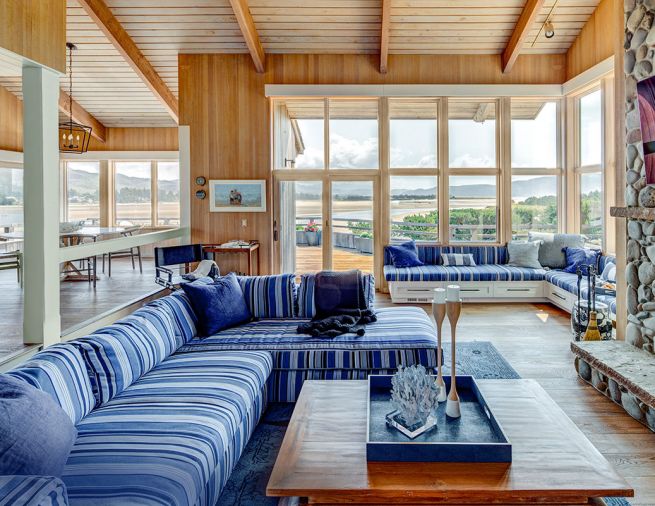 Bold, beachy stripes anchor the great room seating for cozy all season views. Original cedar work was preserved throughout, while the fireplace was replaced with a more place-appropriate river-rock façade with limestone hearth and mantle designed by Ann McCulloch Studio. Pillows, throw, and other accessories from Ann McCulloch Studio.