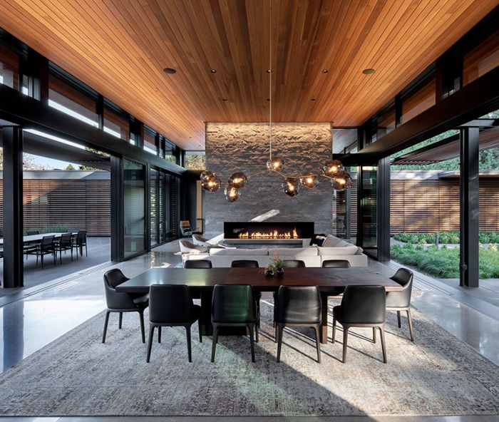 The homeowner’s love for Japanese architecture inspired Berry’s great room flanked by dual 35  Weiland Aluminum/Wood Liftslide doors from Portland Millwork and grounded by Island Stone split face silver quartzite fireplace. Biella Lighting Design.