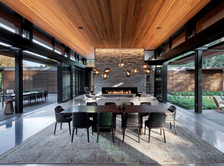 The homeowner’s love for Japanese architecture inspired Berry’s great room flanked by dual 35  Weiland Aluminum/Wood Liftslide doors from Portland Millwork and grounded by Island Stone split face silver quartzite fireplace. Biella Lighting Design.