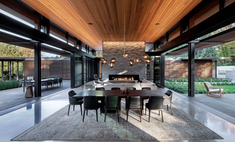 The homeowner’s love for Japanese architecture inspired Berry’s great room flanked by dual 35' Weiland Aluminum/Wood Liftslide doors from Portland Millwork and grounded by Island Stone split face silver quartzite fireplace. Biella Lighting Design.