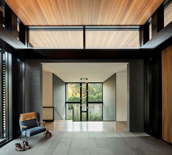 Entry foyer brings outside elements in with textured obsidian granite flooring. Berry introduces structural elements of steel, wood, stone + glass. Quentin lounge chair. Staircase down to “hidden floor.”