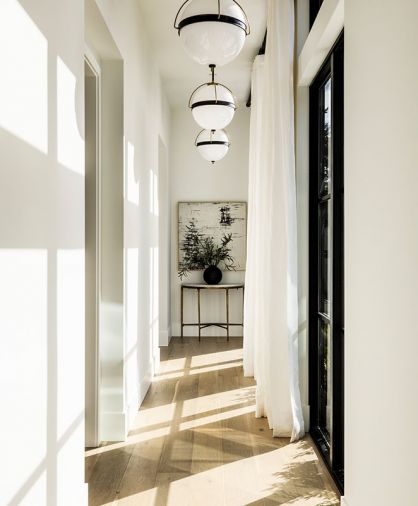 In the “Sun Hall,” oak floors from CR Floors are warmed by the expansive windows and Arteriors pendants.