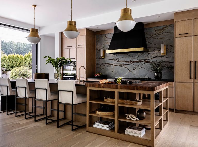 The “wow element” in the kitchen, says Kowalski, is the Pental quartzite slab, which covers the backsplash behind the stove, and is accented with a gorgeous black metal hood, with inset Vent-A-Hood, flanked by sconces from Arteriors. Brass accents, including a Brizo faucet and pendants by Circa Lighting, warm the space, alongside the walnut endgrain butcher block counter by Grothouse that wraps the end of the island.