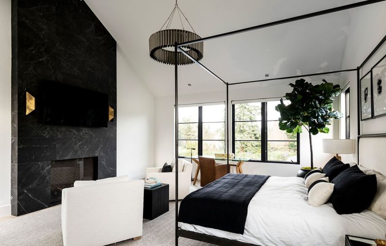 Kowalski prioritized relaxation in the main suite. Pental tile composes the fireplace surround and meets the tall ceiling. Arteriors sconces bookend a television. The modern four-poster bed is from Restoration Hardware.